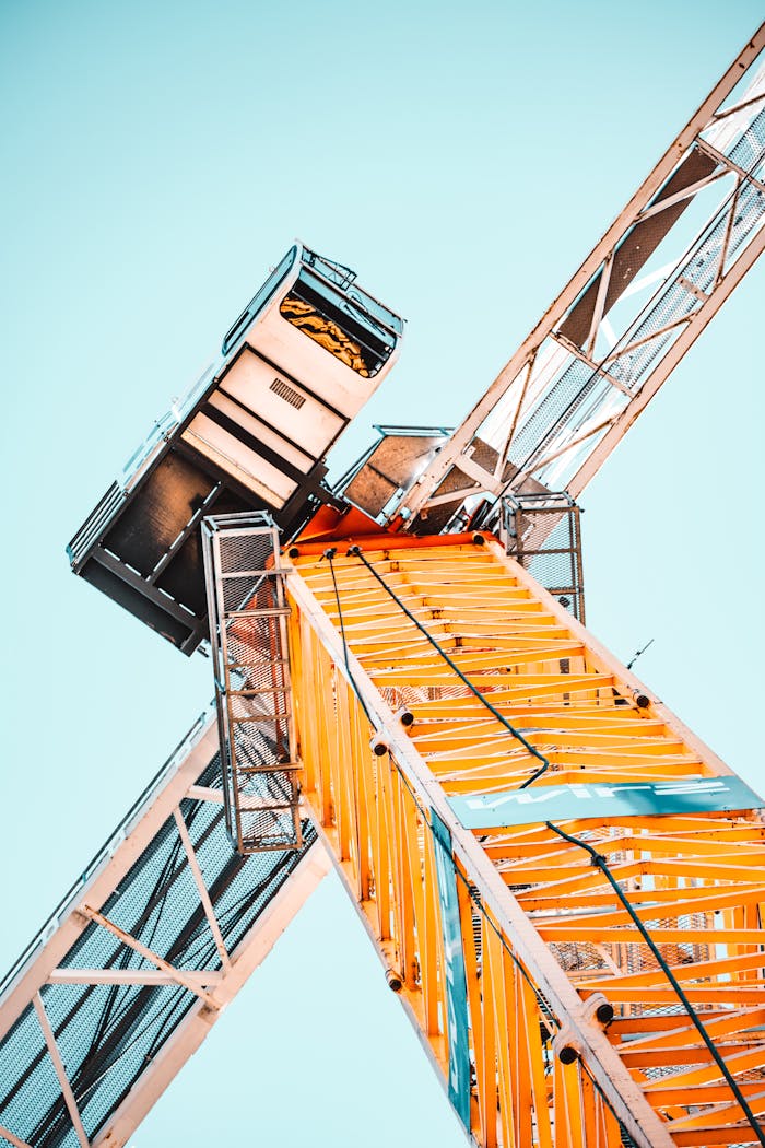 services-01 A striking low angle shot of a vibrant yellow tower crane against a clear sky, showcasing industrial power.